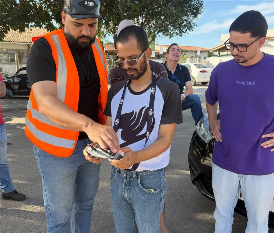 Instrutor orientando um aluno no controle do drone durante a aula prática